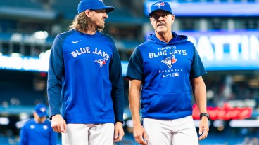 Kevin Gausman #34 of the Toronto Blue Jays walks to the dugout with pitching coach Pete Walker before playing the Boston Red Sox in their MLB game at the Rogers Centre.